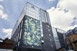A modern building with a glass facade and a large mosaic artwork on one side.