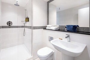 Ein modernes Badezimmer mit einer Duschkabine, einer weißen Toilette und einem Waschbecken mit Spiegel.