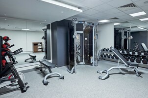 A gym with cardio equipment, weight machines, and a rack of dumbbells.