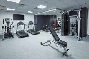 A gym with treadmills, elliptical machines, a bench press, and weightlifting equipment.