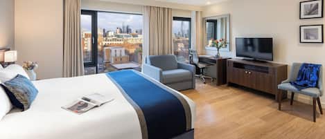 Habitación de hotel moderna con una cama grande, un escritorio, un televisor y vistas a la ciudad.
