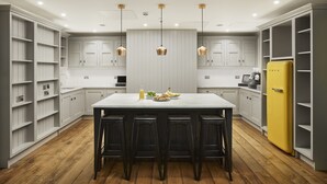Une cuisine moderne avec un îlot central, des tabourets de bar et un réfrigérateur jaune.
