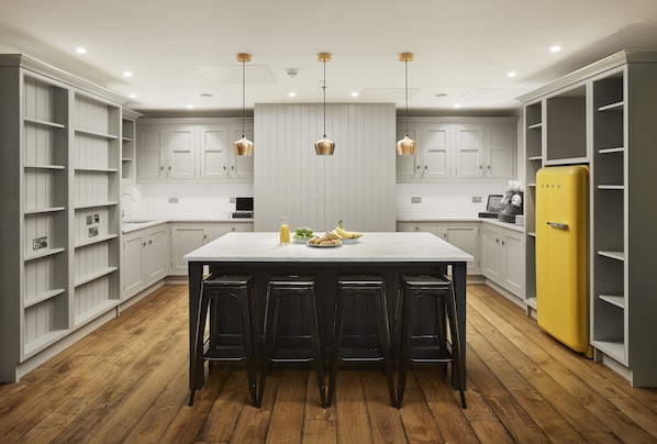 A modern kitchen with a central island, bar stools, and a yellow refrigerator.