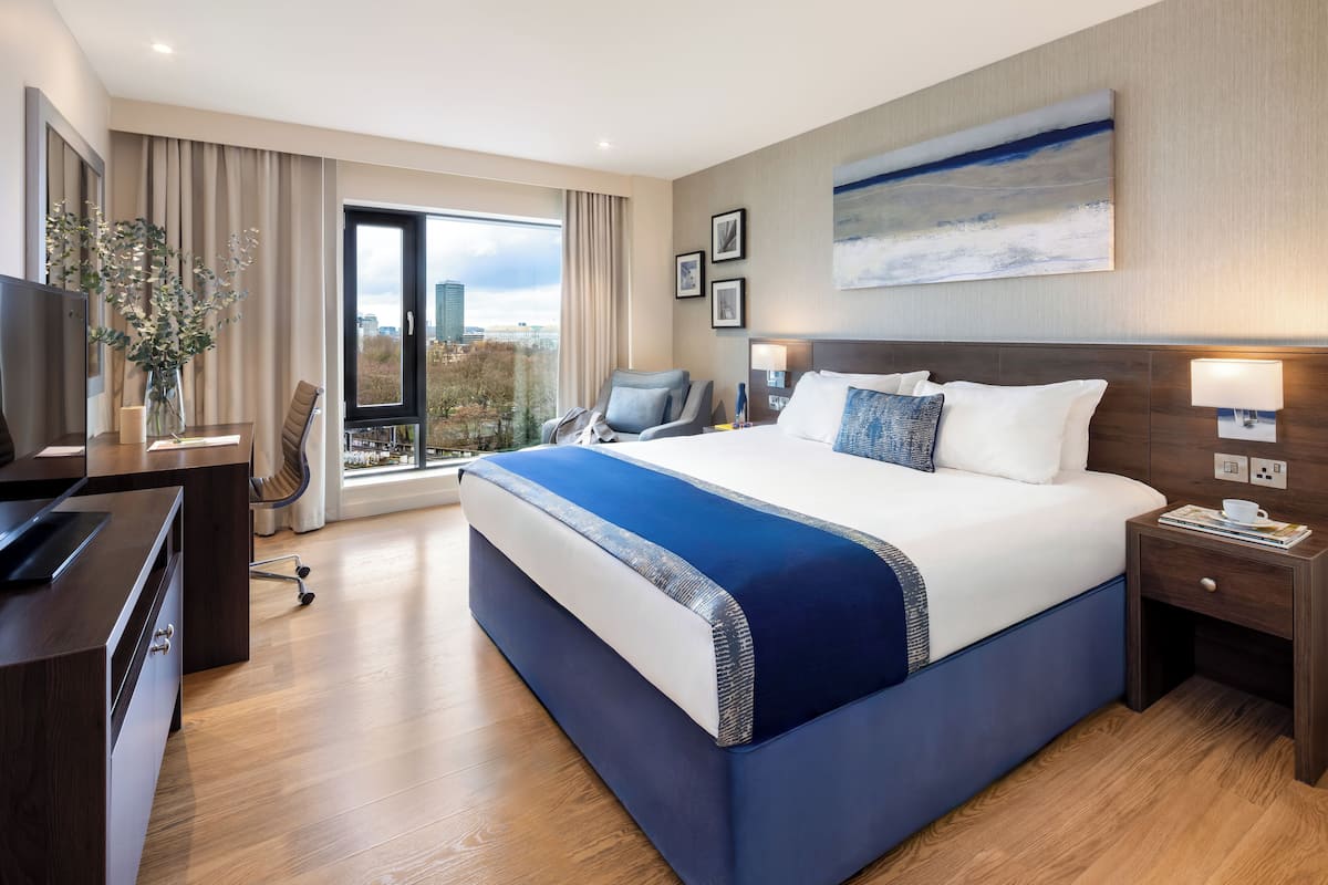 Une chambre d’hôtel moderne équipée d’un grand lit, d’un bureau, d’une chaise et d’un téléviseur.