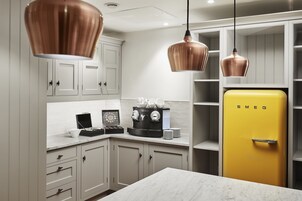 A kitchen with white cabinets, a yellow refrigerator, and copper pendant lights.