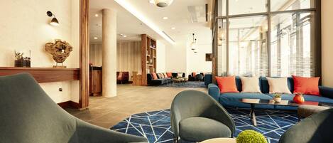 Een moderne hotelentree met een zithoek, een salontafel en een groot raam.