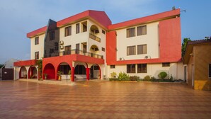 Un edificio de varios pisos con fachada roja y blanca, que presenta un patio central con suelo de baldosas.
