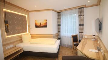 Une chambre d’hôtel avec un lit, un bureau, une chaise, une télévision et un tableau au mur.