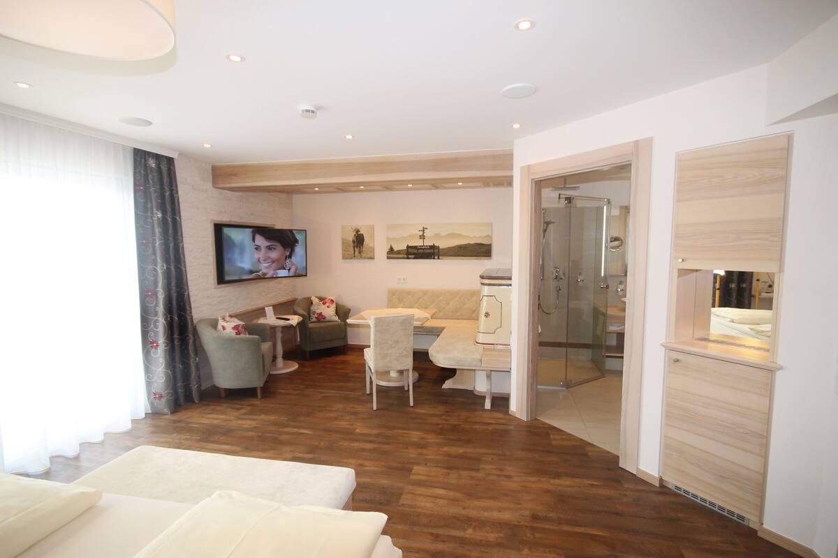 Una sala moderna con sofá, televisor y comedor con mesa y sillas.