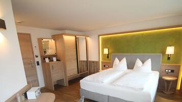 Ein Hotelzimmer mit Bett, Nachttischlampen, einem Spiegel, einem Kleiderschrank und einem kleinen Tisch mit Lampe.
