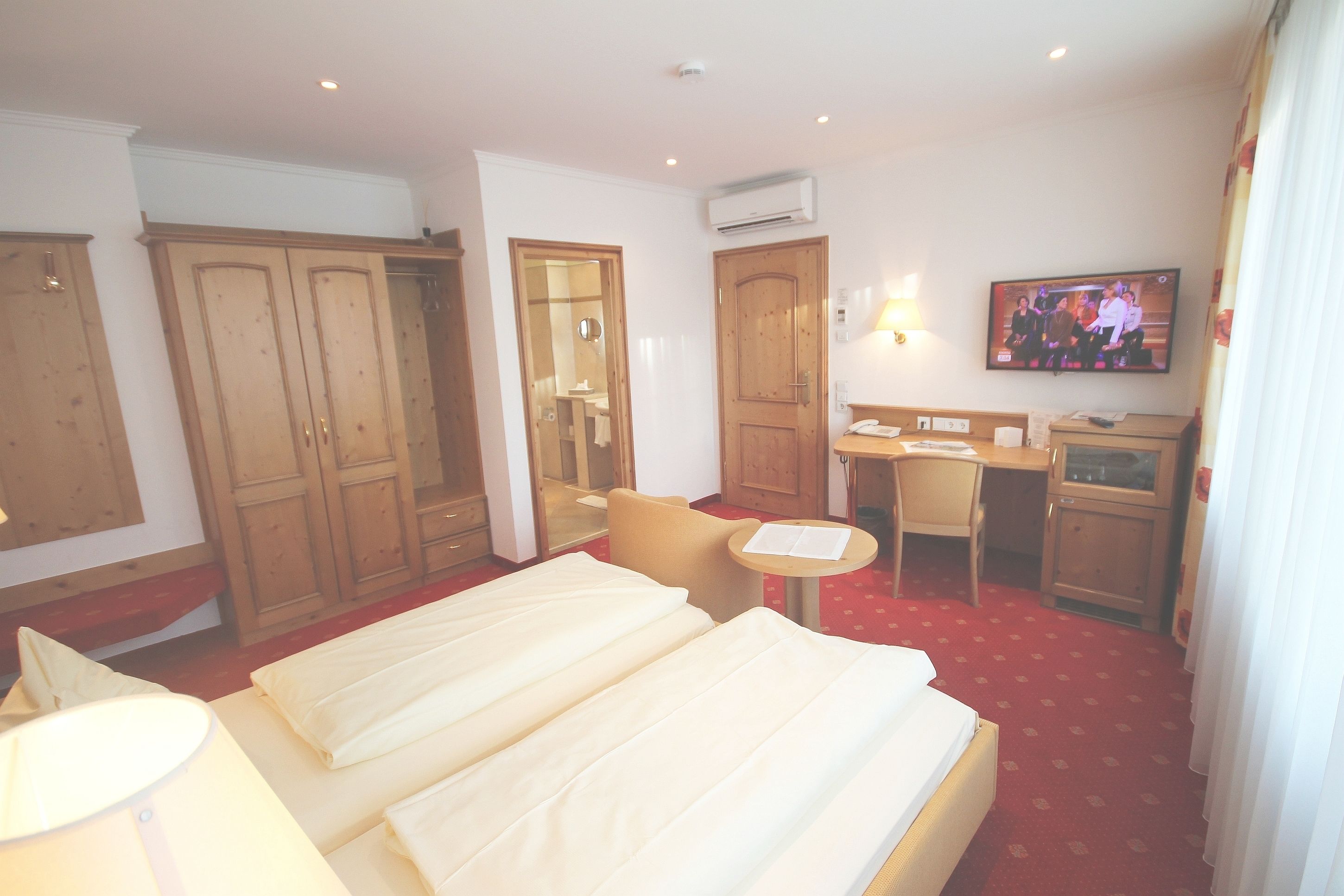 Une chambre d’hôtel avec deux lits, un bureau, une chaise, une télévision et une armoire.