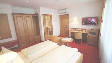 Une chambre d’hôtel avec deux lits, un bureau, une chaise, une télévision et une armoire.