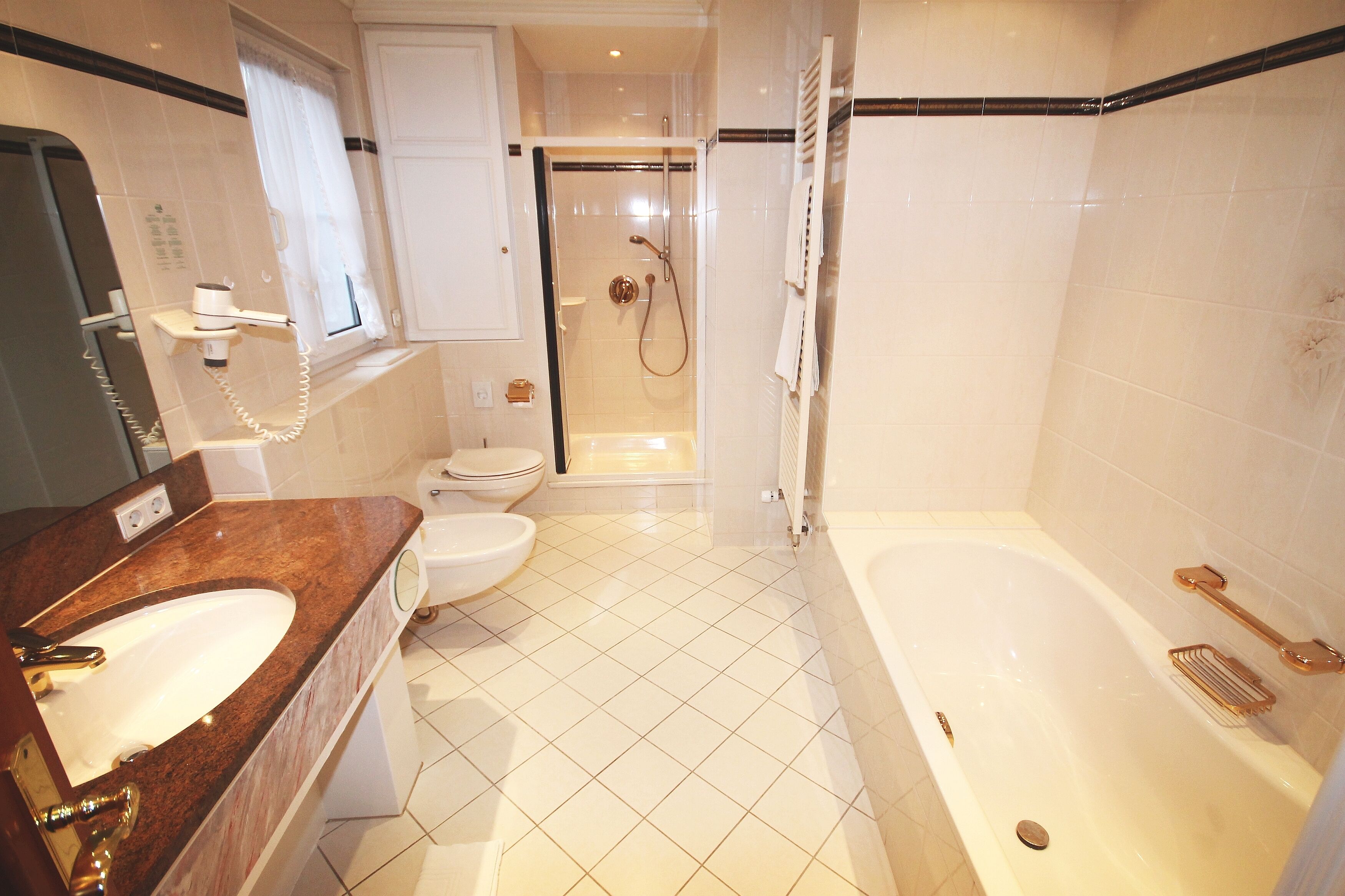 Une salle de bain moderne équipée d’une baignoire, d’un lavabo, de toilettes et d’un espace douche.