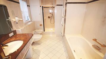 Une salle de bain moderne équipée d’une baignoire, d’un lavabo, de toilettes et d’un espace douche.