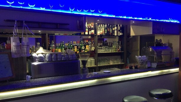 A bar area with a counter, stools, and shelves stocked with bottles and glasses. - Primavera Hotel (Mestre)