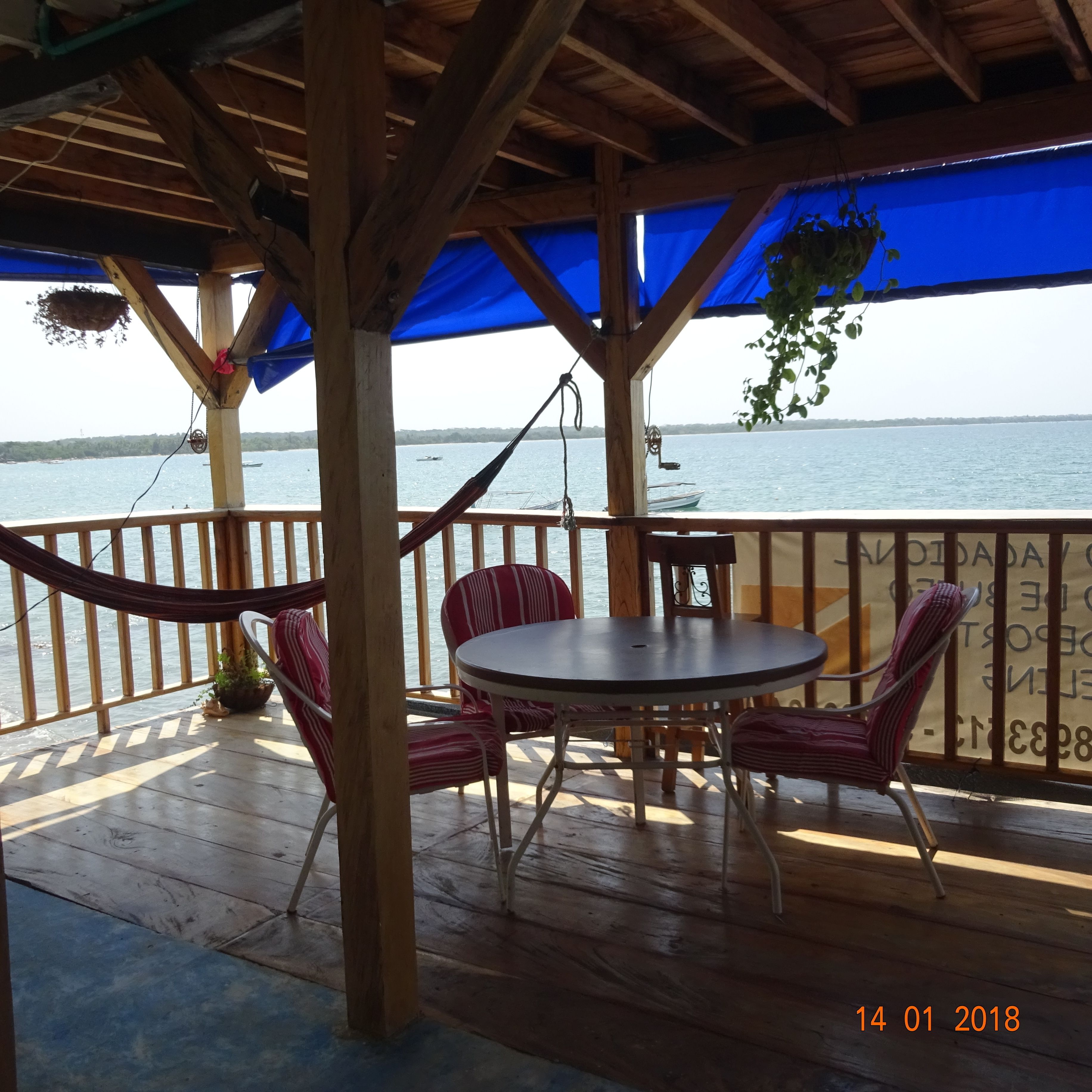 A wooden deck with a table and chairs, overlooking a body of water.