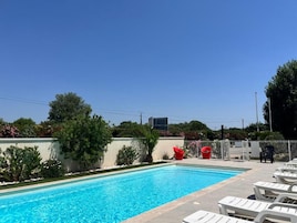 A swimming pool with lounge chairs and a fenced area with red chairs.