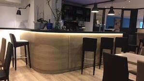 Un espace bar moderne avec un comptoir incurvé, des tabourets de bar noirs et un plancher en bois.