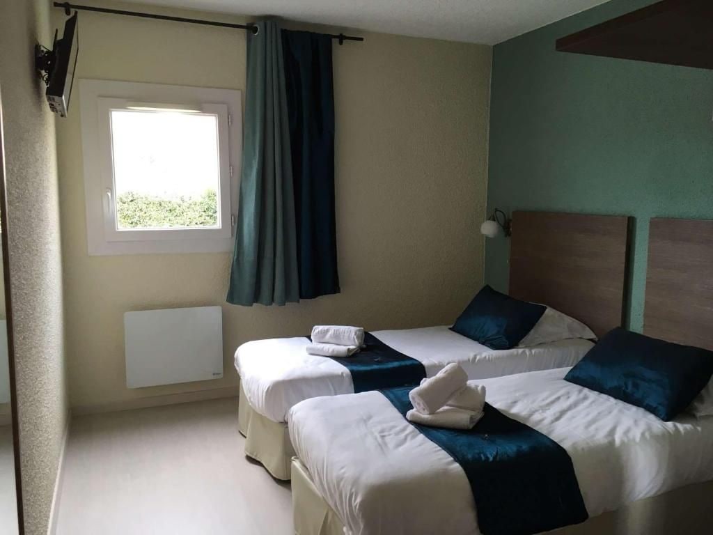 Ein Hotelzimmer mit zwei Betten, einem fensterbelaubten Fenster, einem Heizkörper und einer Wandlampe.