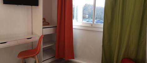 A room with a desk, chair, and a red sofa.