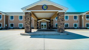 A building with a stone facade, a covered entrance, and a logo on the front. - Cobblestone Hotel & Suites - Paxton (Paxton)