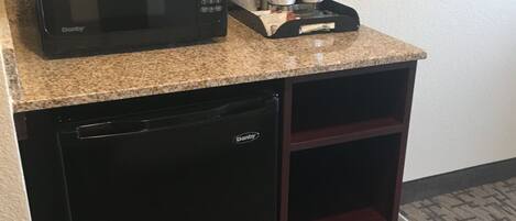 A compact kitchenette with a microwave, coffee maker, and a small refrigerator.