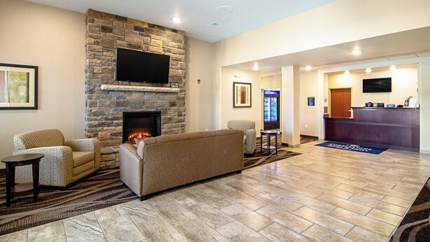 A spacious lobby with a stone fireplace, comfortable seating, a reception desk, and a flat-screen TV mounted on the wall. - Cobblestone Hotel & Suites - Paxton (Paxton)