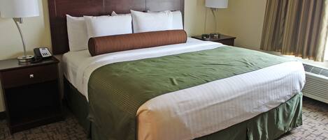 A hotel room with a large bed, two bedside tables, a telephone, and a window with curtains.