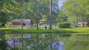 A serene park with a pond, trees, and a gazebo.