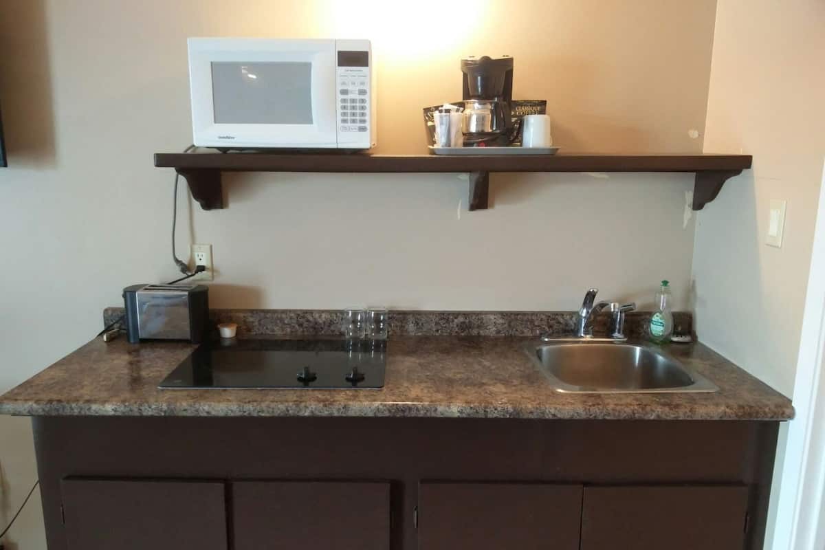 A kitchen with a microwave, toaster, coffee maker, and a sink.