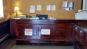 Una reception con un cartello delle politiche di pagamento, un cartello che indica l'orario di check-out e una bacheca con avvisi.