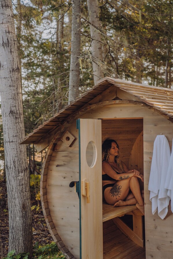 A wooden cabin with a circular door, a small window, and a towel hanging on the wall.
