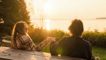Zwei Personen sitzen bei Sonnenuntergang an einem Holztisch draußen.