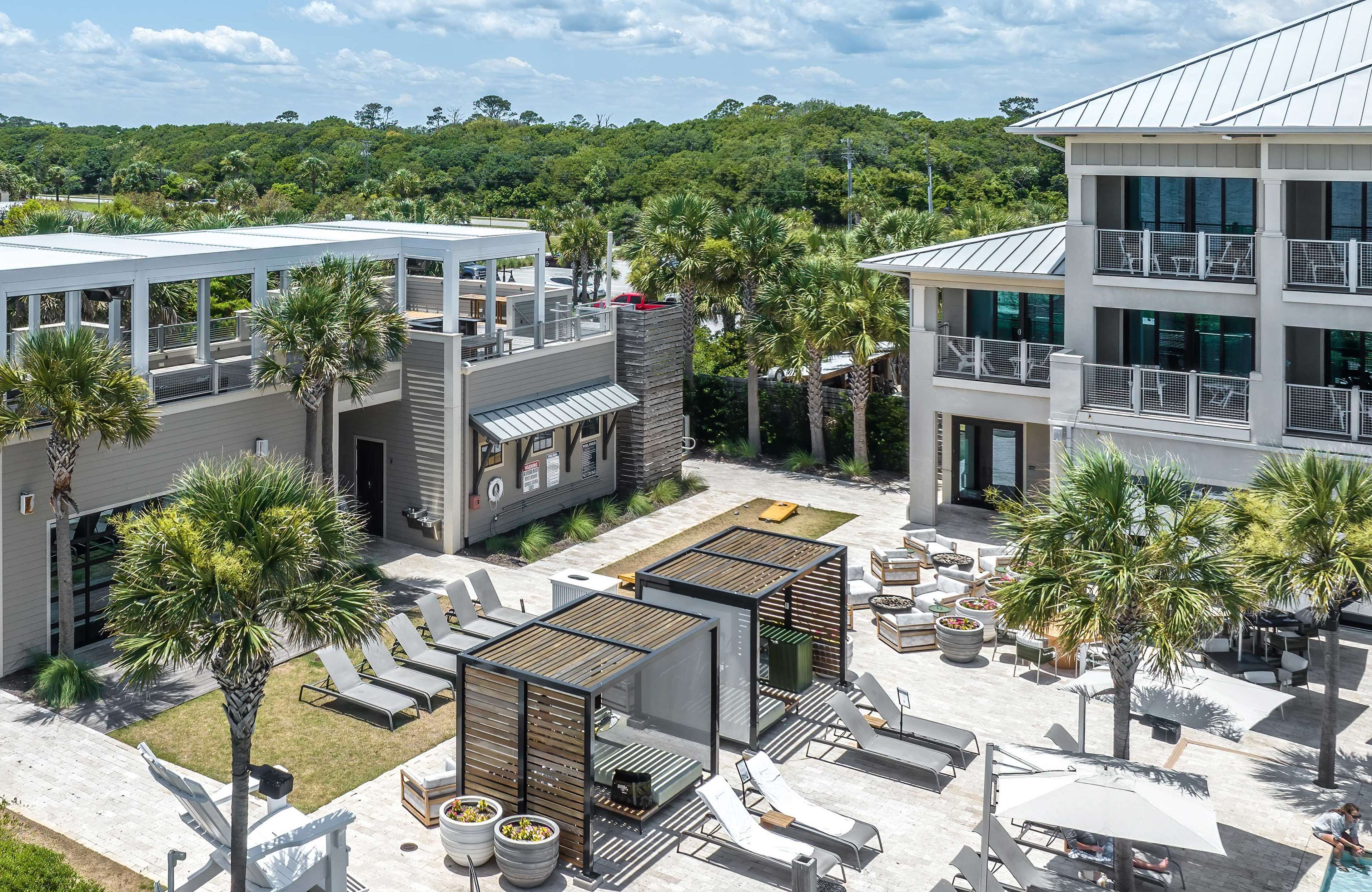 A modern outdoor lounge area with sun loungers, a pool, and a view of a lush green landscape.