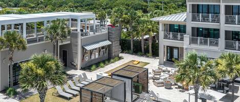 A modern outdoor lounge area with sun loungers, a pool, and a view of a lush green landscape.