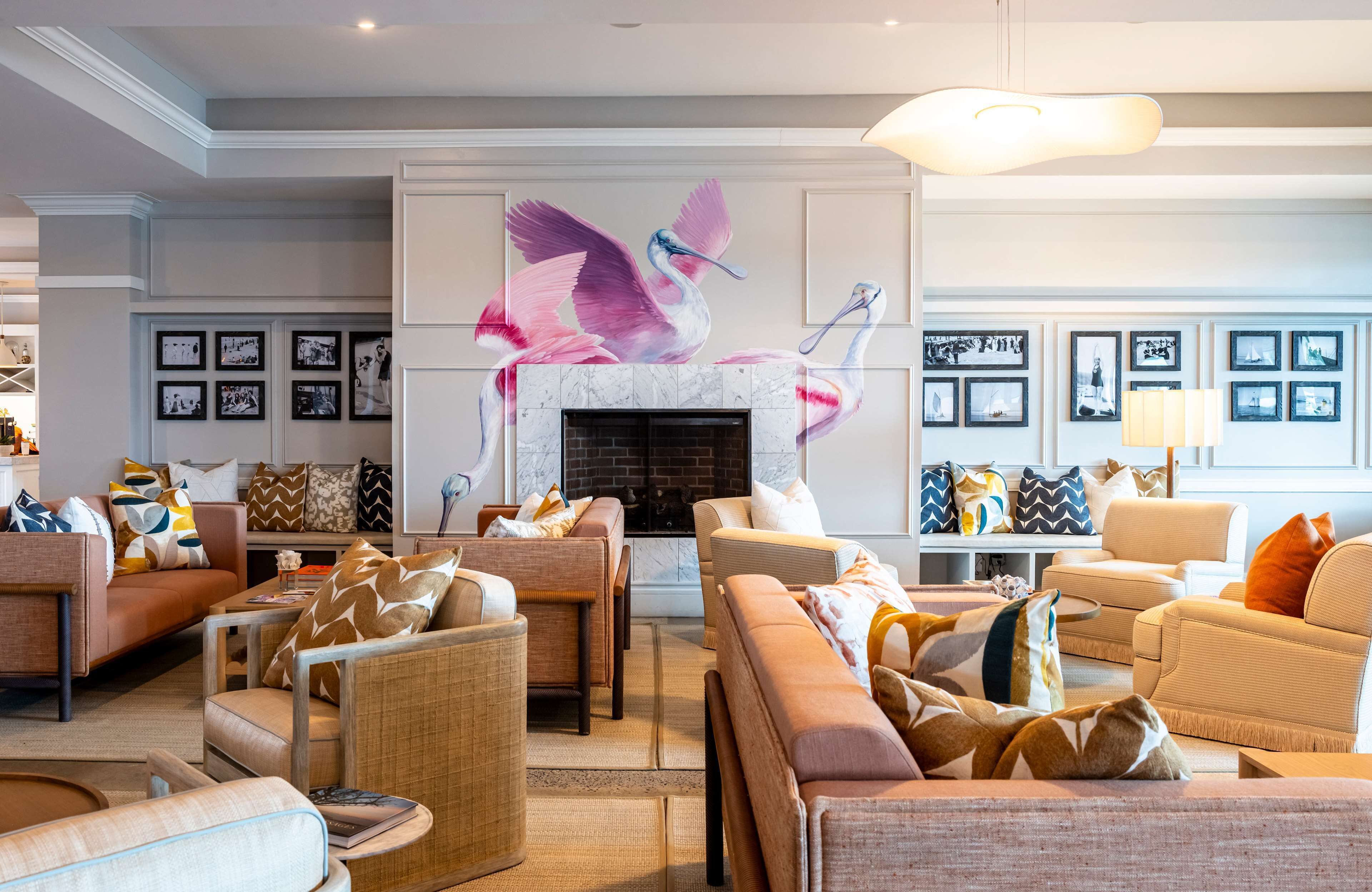 A spacious living room with a fireplace, comfortable seating, and a large wall mural.