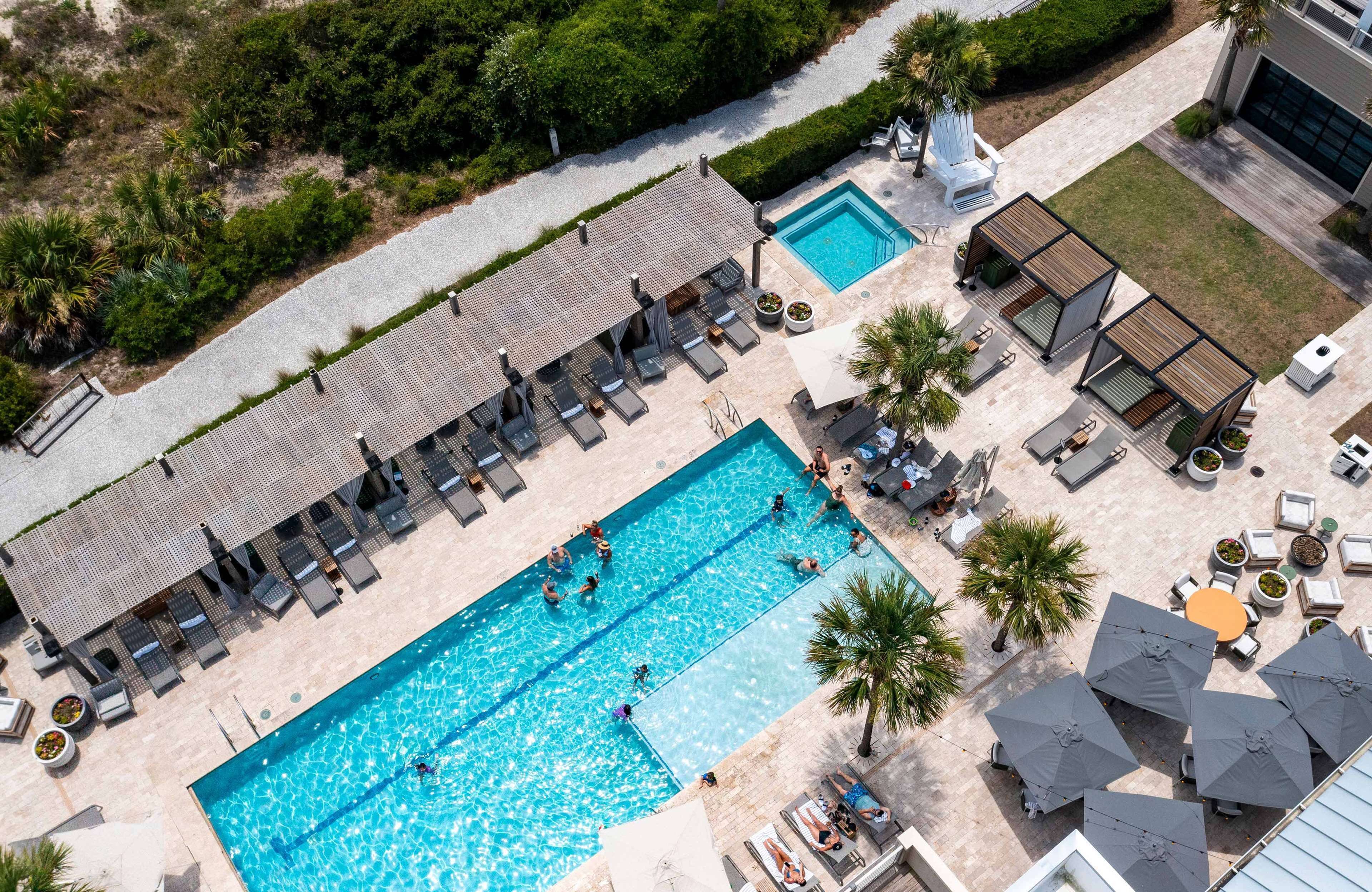 Vue aérienne d’un complexe hôtelier doté de deux piscines, d’espaces de détente et d’un espace de repos abrité.