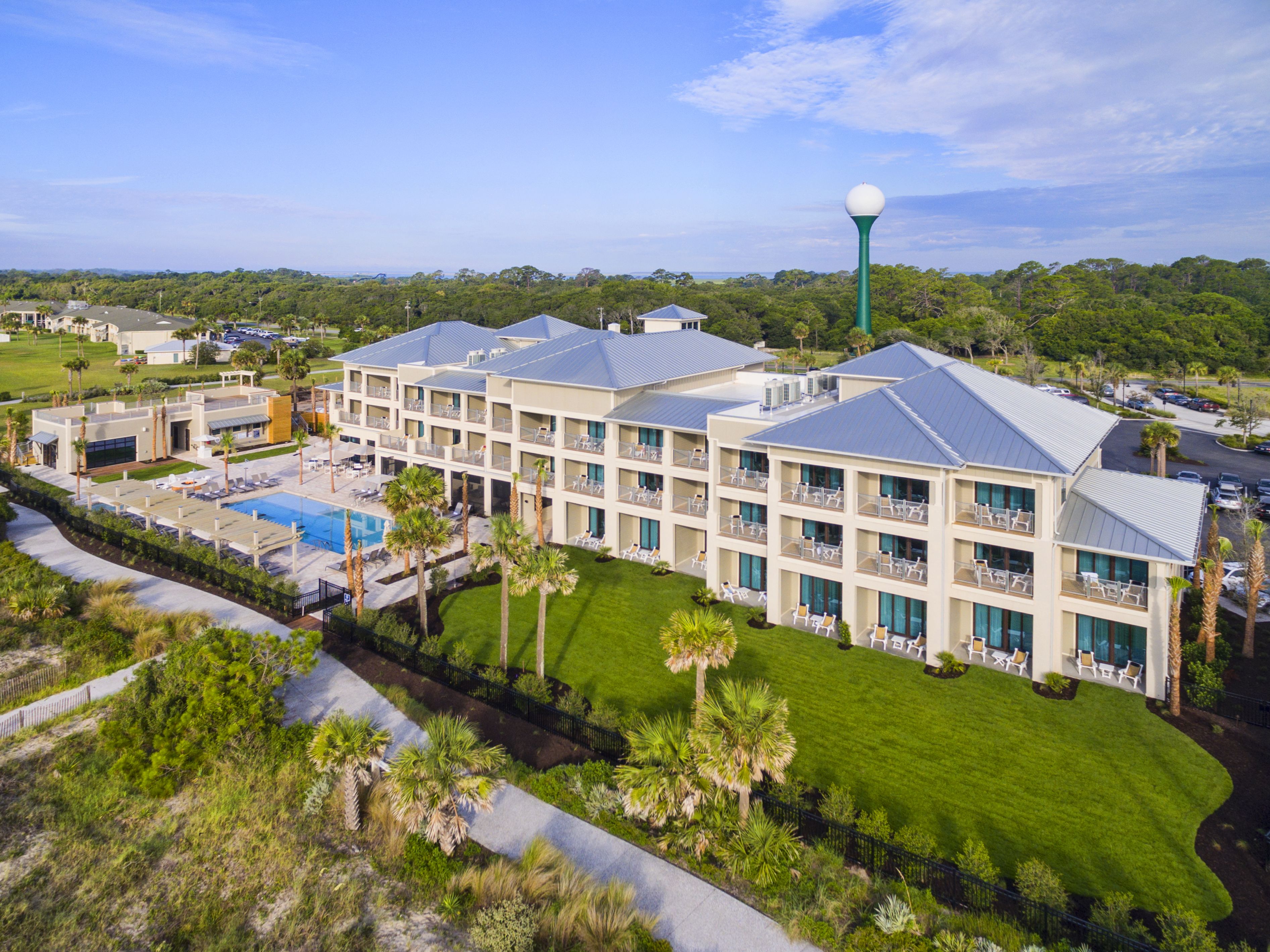 A hotel with multiple floors, a swimming pool, and a golf course in the background.