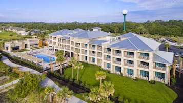 A hotel with multiple floors, a swimming pool, and a golf course in the background.