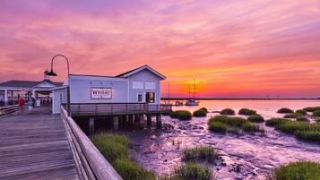 A wooden pier leading to a white building with a sign reading "WHARF".