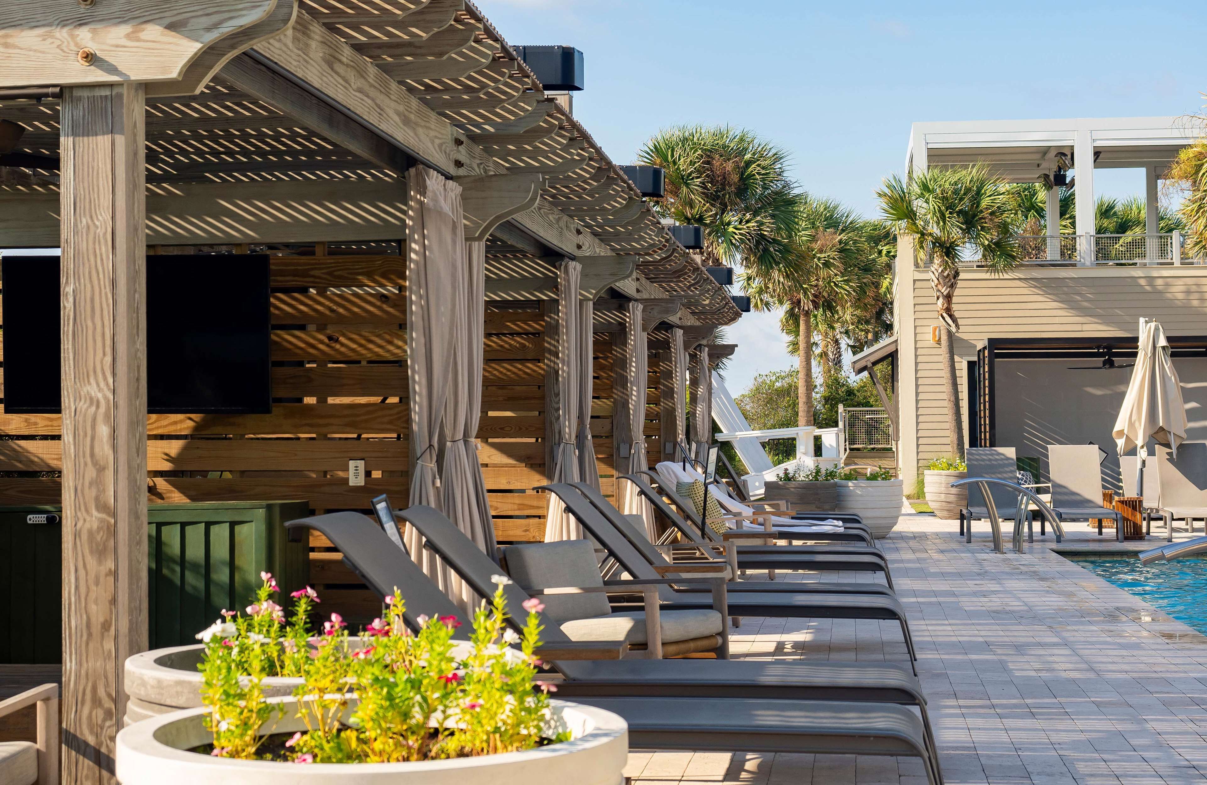 A poolside area with lounge chairs, a pool, and a wooden pergola structure.
