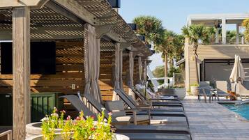 A poolside area with lounge chairs, a pool, and a wooden pergola structure.