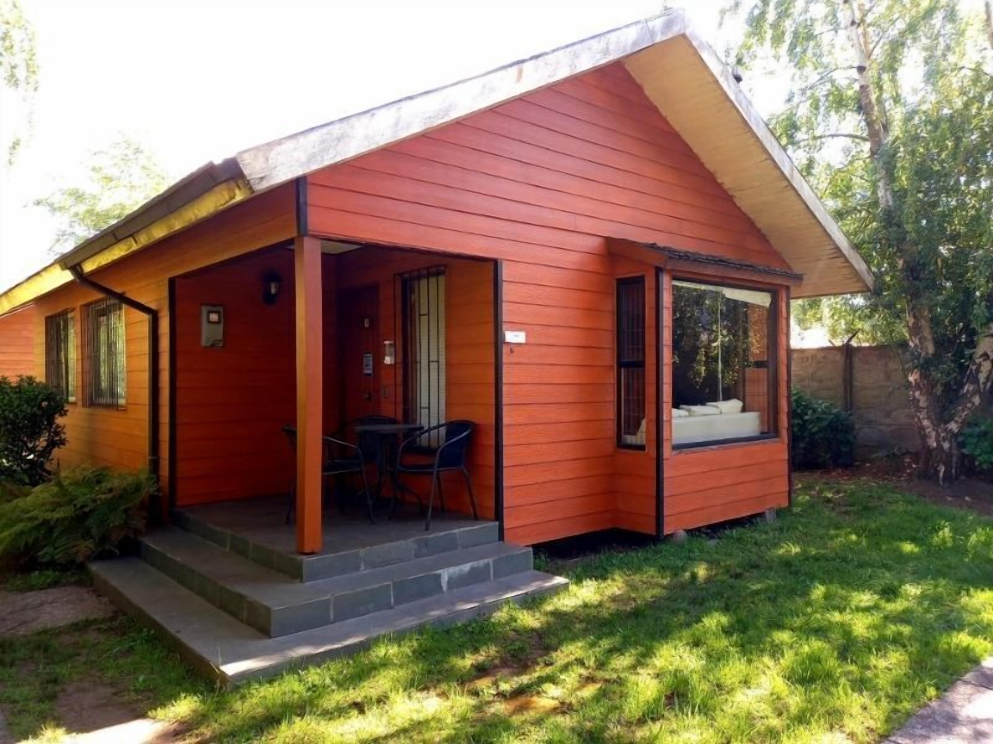 Einbungalow mit Veranda, einem kleinen Tisch und Stühlen sowie einem Fenster.