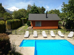 Una piscina al aire libre, sombrillas, sillones reclinables de piscina