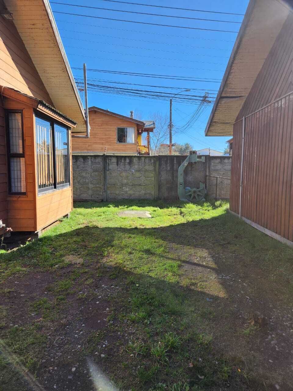 A residential property with a fenced yard, a wooden house, and a stone wall.
