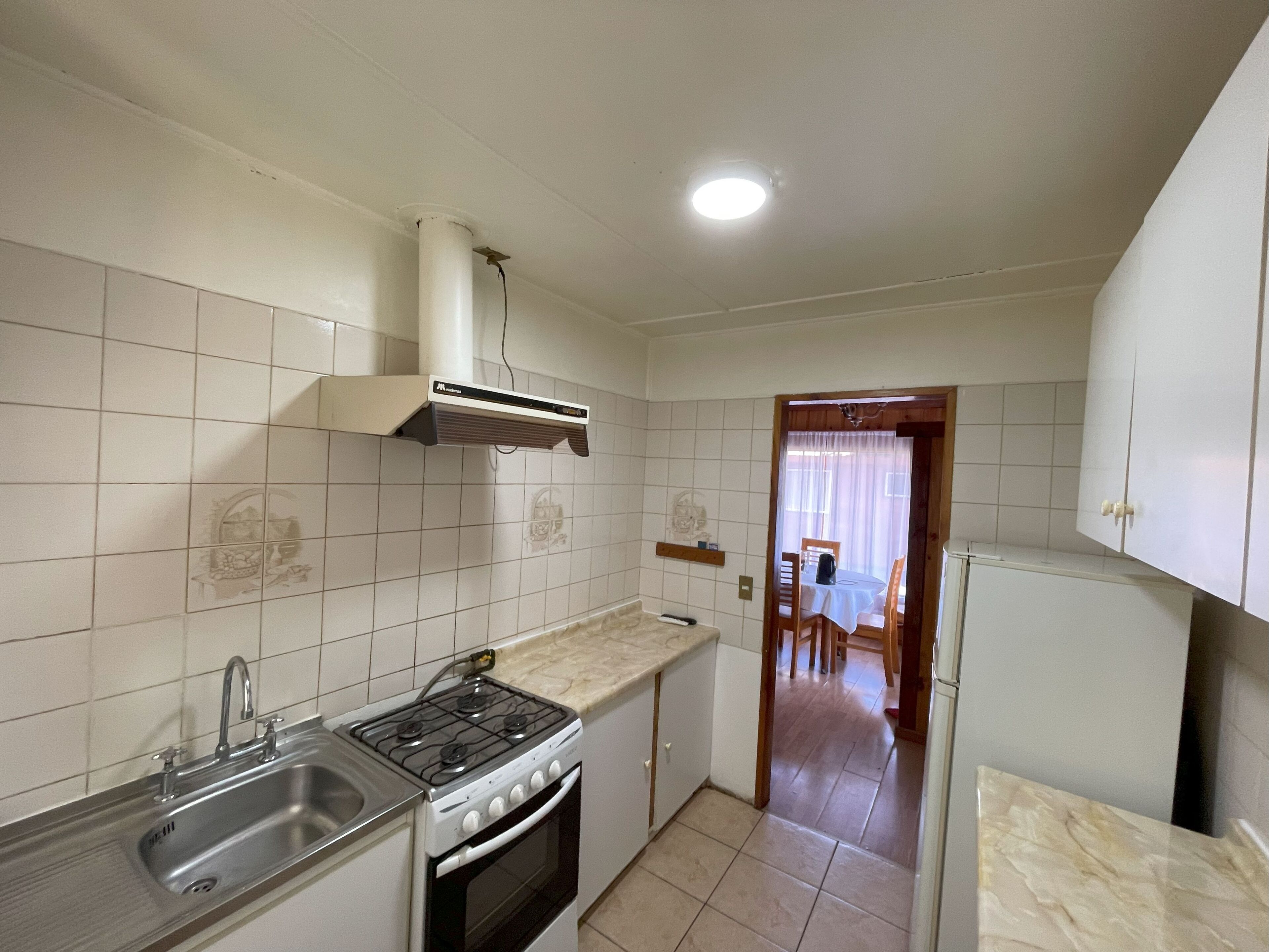 A kitchen with a gas stove, sink, and a white refrigerator.