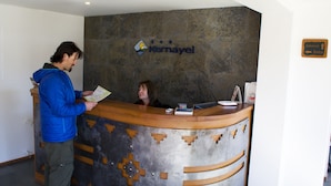 A reception desk with a logo and a sign indicating internet and Wi-Fi availability. - Cabañas Kernayel (Pucón)