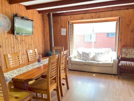 Interior de madera con una mesa de comedor, sillas, un sofá y un televisor.