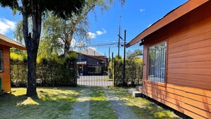 A residential property with a paved driveway, a wooden fence, and a large tree. - Cabañas Kernayel (Pucón)
