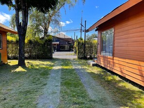 Una propiedad residencial con entrada pavimentada, cerca de madera y un gran árbol.